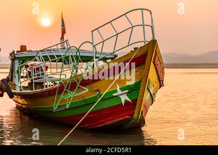 Bateau aux couleurs du drapeau du Myanmar sur les rives de la rivière Irrawaddy au coucher du soleil de Bagan, au Myanmar
