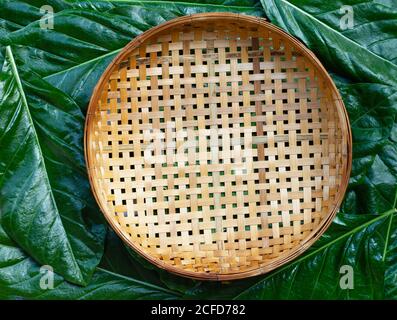 Panier de battage en bambou en bois vide sur Noni ou Morinda Citrifolia laisse le fond. Vue de dessus Banque D'Images