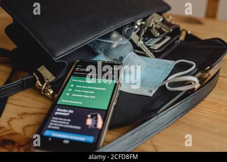 Contenu d'un sac à main pour femmes pendant les périodes de corona: Protection de la bouche, application d'avertissement de corona, gel de désinfection Banque D'Images