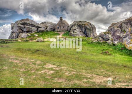 Maison en pierre entre deux immenses rochers de granit, site de Meneham, Meneham, Bretagne, France Banque D'Images