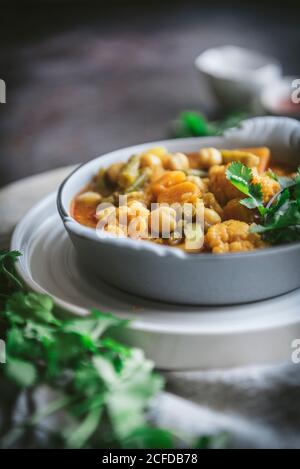 Bol avec savoureux curry de pois chiches et herbes placées près de gris serviette en tissu dans un cadre rustique Banque D'Images