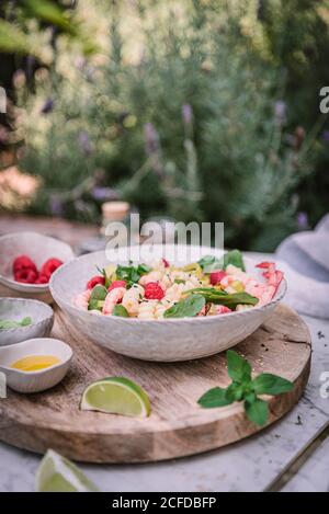 De la salade et de la sauce appétissantes au-dessus de la lime de baies support en bois avec sel et poivre sur la table Banque D'Images