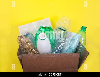 Les déchets des bouteilles en plastique dans une boîte en carton sur fond jaune. Aucun gaspillage. Pureté Banque D'Images