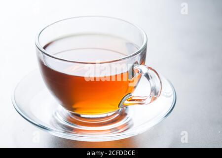 Gros plan en verre de thé chaud aromatique placé sur la soucoupe sur table à la cafétéria Banque D'Images