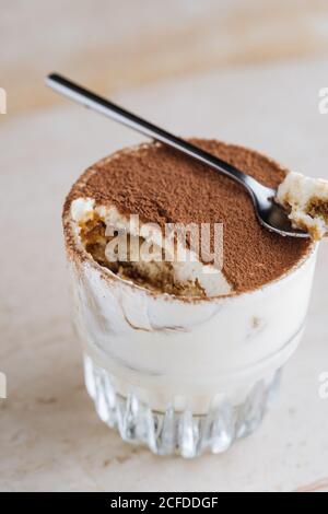 Du haut délicieux tiramisu de dessert traditionnel aromatisé au café servi dans verre sur la table Banque D'Images