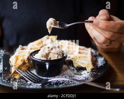 personne méconnaissable qui apprécie la glace douce froide et les gaufres fraîches pendant le déjeuner dans le café Banque D'Images