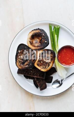 Vue de dessus des tranches d'aubergine fumées arrondies sur blanc assiette avec sauce rouge oignon vert et croûtons frits de pain de seigle dans le restaurant Banque D'Images