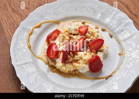 Du dessus du fromage cottage sur plaque blanche servi avec tranches de noix de fraise fraîches rouges et de caramel Banque D'Images