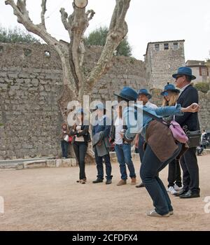 Saint-Paul-de-Vence France la posture parfaite pour lancer une balle. Chaque membre de l'équipe, jeunes femmes et jeunes hommes, porte un chapeau bleu. Banque D'Images