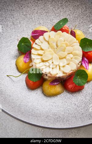 De dessus de délicieux tartare de poisson servi avec des amandes et frais tomates cerises sur l'assiette du restaurant Banque D'Images