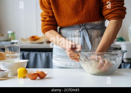 Femme avec de la pâte dans les mains debout à la table Banque D'Images