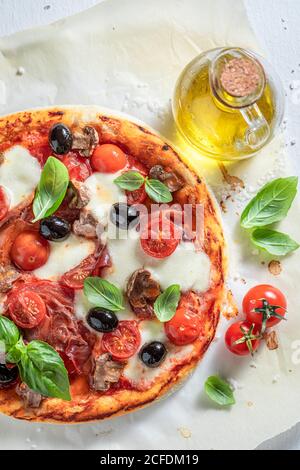 Pizza fraîche Capricciosa faite de tomates, fromage, olives et jambon sur table en bois Banque D'Images