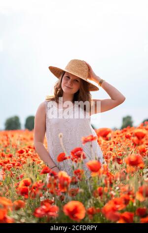 Jeune fille radiante dans un chapeau de paille dans le coquelicot champ Banque D'Images