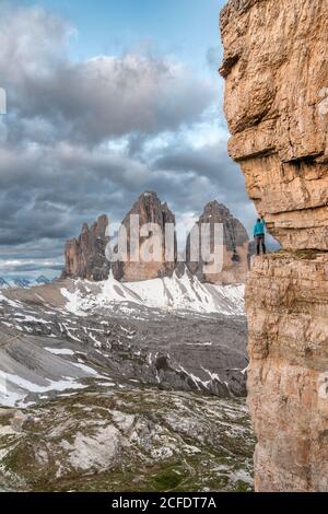 Drei Zinnen, Dolomites, province de Bolzano, Tyrol du Sud, Italie. Un alpiniste admire le panorama de la montagne sur un groupe de rock exposé Banque D'Images