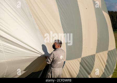 Allemagne, Saxe-Anhalt, Fir, pilote avec masque se tient sur l'enveloppe de son ballon à air chaud. Banque D'Images