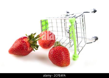 Petit chariot de supermarché avec fraises éparpillées Banque D'Images