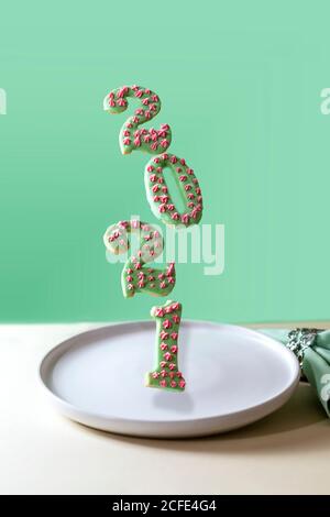 Biscuits volants, pain d'épice sous la forme des numéros 2021 du nouvel an sur fond vert. Bonne année 2021 et Joyeux Noël. La lévitation alimentaire. Banque D'Images