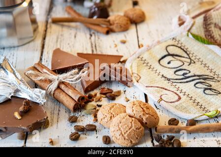 Bâtons de Cinammon attachés avec corde de jute, cafetière, bonbons et biscuits sur un fond de bois blanc. Pause-café ou petit déjeuner en toile de fond. Banque D'Images