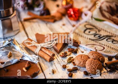 Bâtons de Cinammon attachés avec corde de jute, cafetière, bonbons et biscuits sur un fond de bois blanc. Pause-café ou petit déjeuner en toile de fond. Banque D'Images