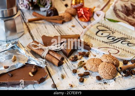 Bâtons de Cinammon attachés avec corde de jute, cafetière, bonbons et biscuits sur un fond de bois blanc. Pause-café ou petit déjeuner en toile de fond. Banque D'Images