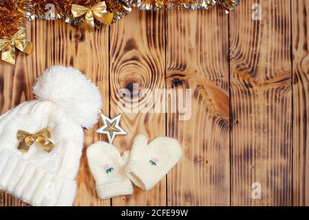 Bonnet et moufles tricotés sur une table en bois. Hiver fond plat. Banque D'Images