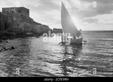 Légende originale : Césarée. (Kaisarieh). Scène de coucher de soleil avec bateau de pêche et pêcheur tirant son filet - emplacement: Israël--Caesarea ca. 1938 Banque D'Images