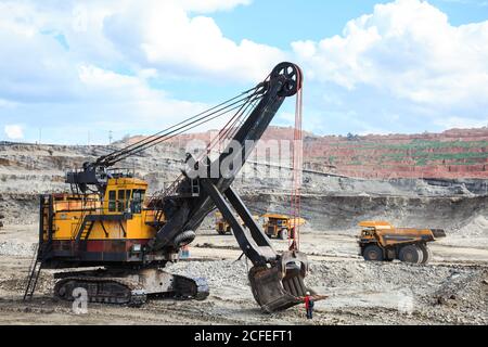 Mine l'équipement lourd travaillant sur le site. La machine est très grande par rapport à un travailleur. Banque D'Images