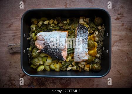 De dessus plat à rôtir avec de grandes pièces de saumon avec peau sur la garniture de légumes et légumes cuits assortis Banque D'Images