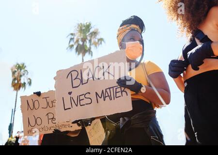 Femme ethnique sérieuse avec une coiffure afro tenant une affiche en carton avec inscription de la vie noire lors de la manifestation dans la ville surpeuplée et claquement Banque D'Images