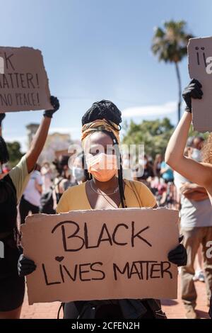 Femme ethnique sérieuse avec une coiffure afro tenant une affiche en carton avec inscription de la vie noire lors de la manifestation dans la ville surpeuplée et claquement Banque D'Images