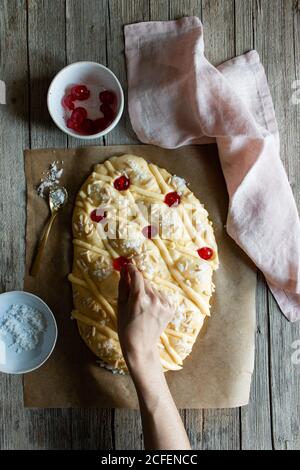 D'en haut personne méconnaissable décorant le Coca de San Juan traditionnel pâtisserie tout en cuisinant sur une table en bois dans la cuisine Banque D'Images