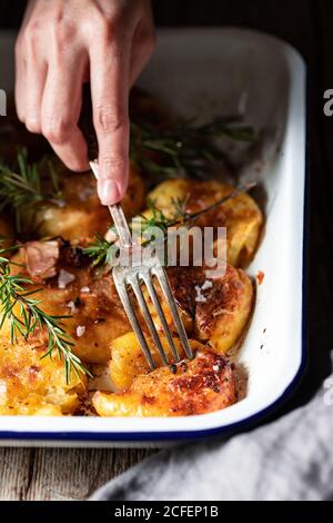 D'en haut, crop man avec fourchette en prenant de délicieuses crevettes frites servi sur une assiette blanche avec du romarin frais et des flocons de sel Banque D'Images