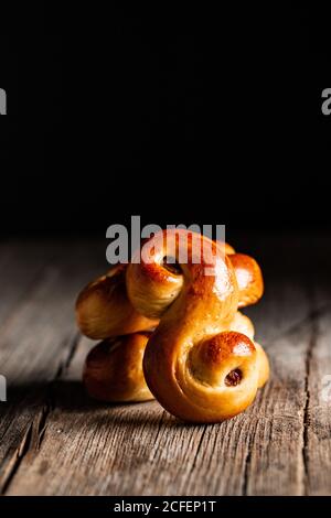 Délicieux petits pains au safran traditionnel frais avec raisins secs table en bois sur fond noir Banque D'Images