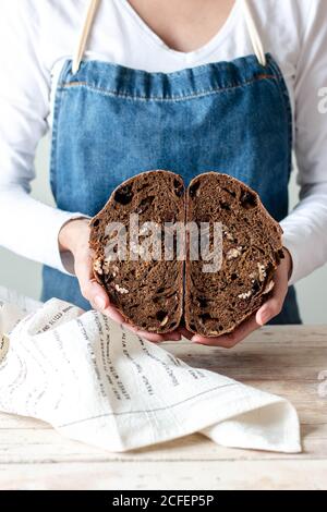 Mains de la femme en tablier tenant le pain de seigle avec les raisins secs et les noix Banque D'Images