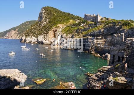 Vue sur la baie de la grotte du Seigneur Byron avec les personnes qui nagent et bronzer sur les rochers et le château de Doria au sommet de la falaise, Porto Venere Banque D'Images