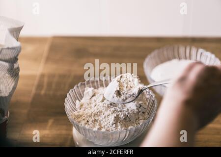 De la récolte ci-dessus anonyme femelle pesant la farine de blé sur électronique balances tout en préparant des ingrédients pour une recette de pâtisserie maison dans la cuisine Banque D'Images