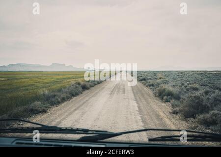 Longue route vide le long de champs verts sans fin par la fenêtre avant De voiture en semi-désert Bardenas Reales Navarra Espagne Banque D'Images