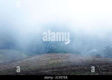 Route asphaltée étroite sur une pente de montagne à travers une épaisse brume dans la nature Banque D'Images