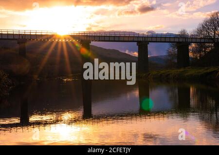 Paysage incroyable avec vieux pont traversant une rivière calme et réfléchi Dans l'eau pendant le coucher du soleil en soirée de printemps en écossais Highlands Banque D'Images