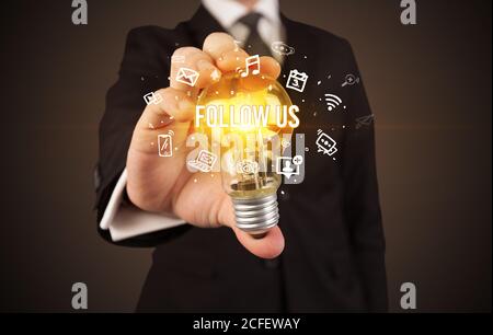 Businessman holding ampoule avec SUIVEZ-NOUS inscription, social media concept Banque D'Images