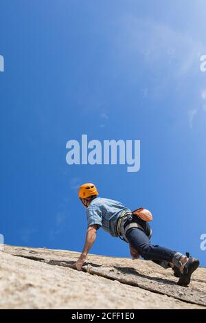 De dessous de l'alpiniste libre méconnaissable escalade dans la nature Banque D'Images