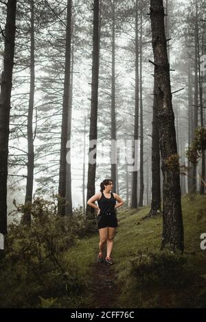 Femme en forme de marche le long du chemin dans la forêt brumeuse Banque D'Images