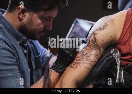 Maître faisant tatouage sur l'avant-bras du client mâle Banque D'Images