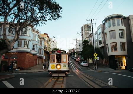 Venice Beach, Etats-Unis - 5 décembre 2017 : bâtiments géométriques et tram avec phare en feu se déplaçant sur le chemin de fer dans la rue avec le panneau jaune Banque D'Images