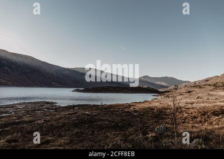 Montagne avec rochers et lac contre ciel bleu clair avec rayons de soleil paysage de nature sauvage en automne Banque D'Images