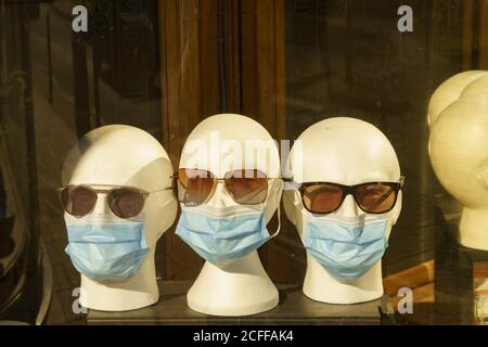 Têtes blanches factices avec lunettes de soleil et masques visibles dans une vitrine d'un opticien, Harrogate, North Yorkshire, Angleterre, Royaume-Uni. Banque D'Images