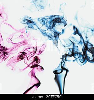 Fumée rose et bleue vibrante translucide et tourbillons de encens aromatiques colorés sur fond blanc Banque D'Images