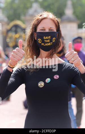 Extinction les militants rebelles à l'extérieur de Buckingham Palace à Londres tiennent une danse de discobedience, le 5 septembre 2020. Un manifestant féminin porte un masque facial disant sauver la planète et des badges XR Banque D'Images