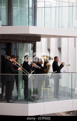 Les membres du public regardent une apparition surprise par un quintette en laiton de l'Orchestre philharmonique royal du bâtiment Beton, qui donne sur les marches espagnoles du parc Wembley. Banque D'Images