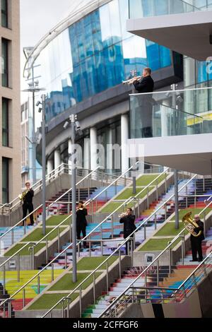 Les membres du public regardent une apparition surprise par un quintette en laiton de l'Orchestre philharmonique royal du bâtiment Beton, qui donne sur les marches espagnoles du parc Wembley. Banque D'Images